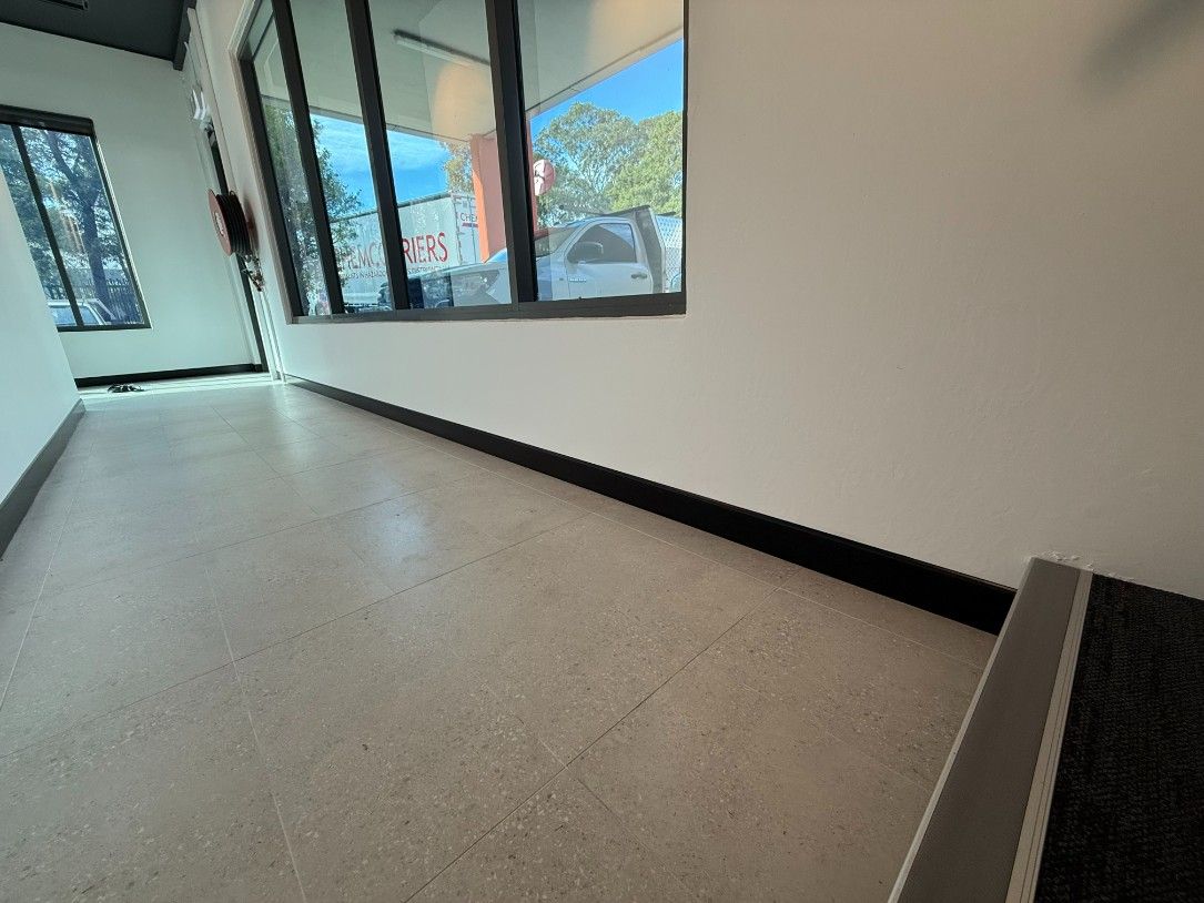 A Hallway With a White Floor and Black Trim and a Window — JOA - Construction & Maintenance Pty Ltd in Appin, NSW