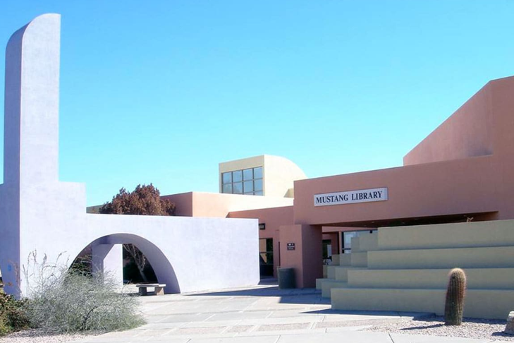 Modern building entrance with white and tan geometric architecture under a clear blue sky