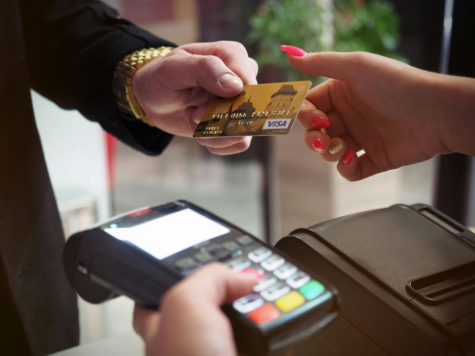 Card being handed to a payment terminal during a contactless checkout transaction.