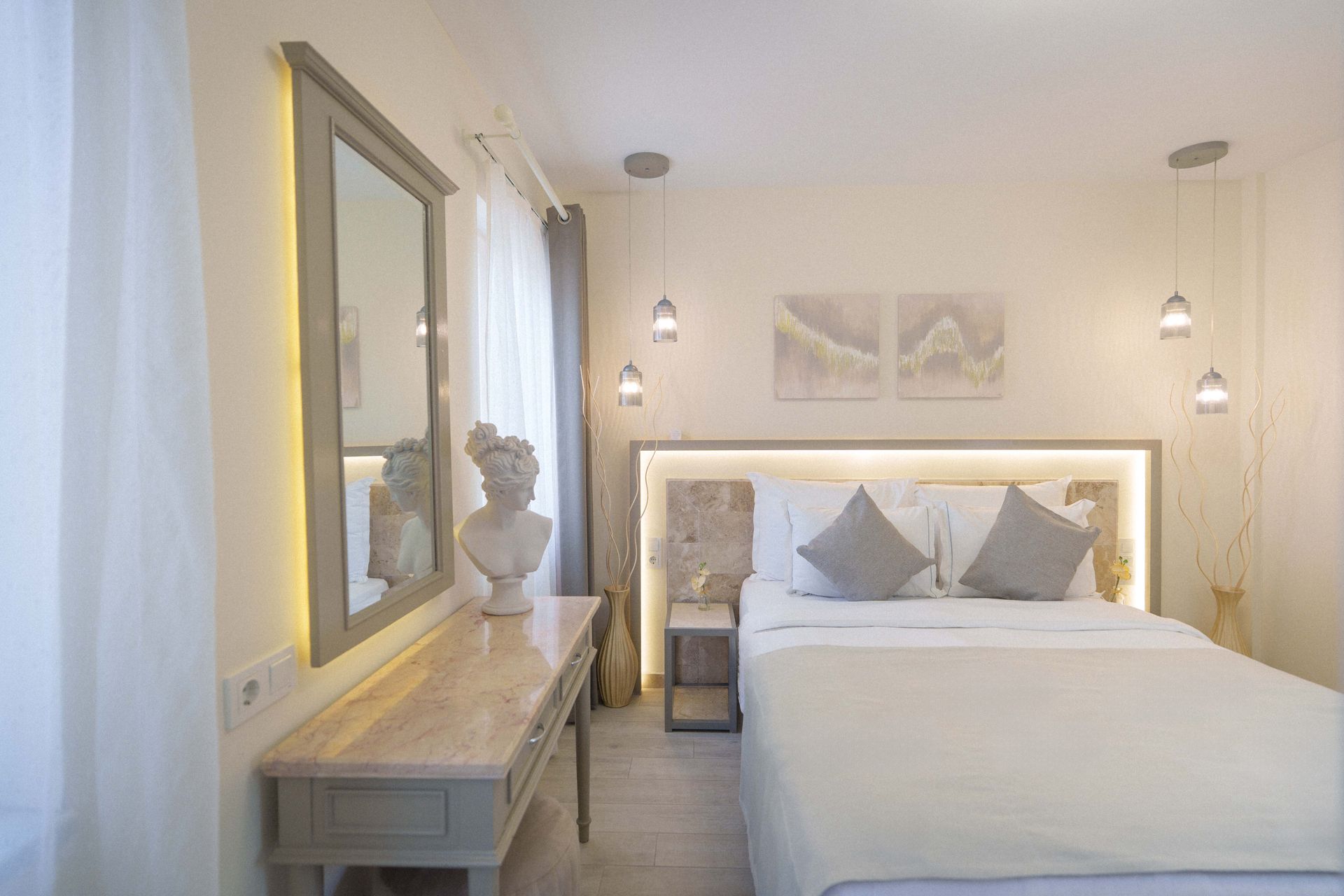 Elemanta Boutique Hotel |Bright bedroom with a neatly made bed, mirrored dresser, and soft white decor