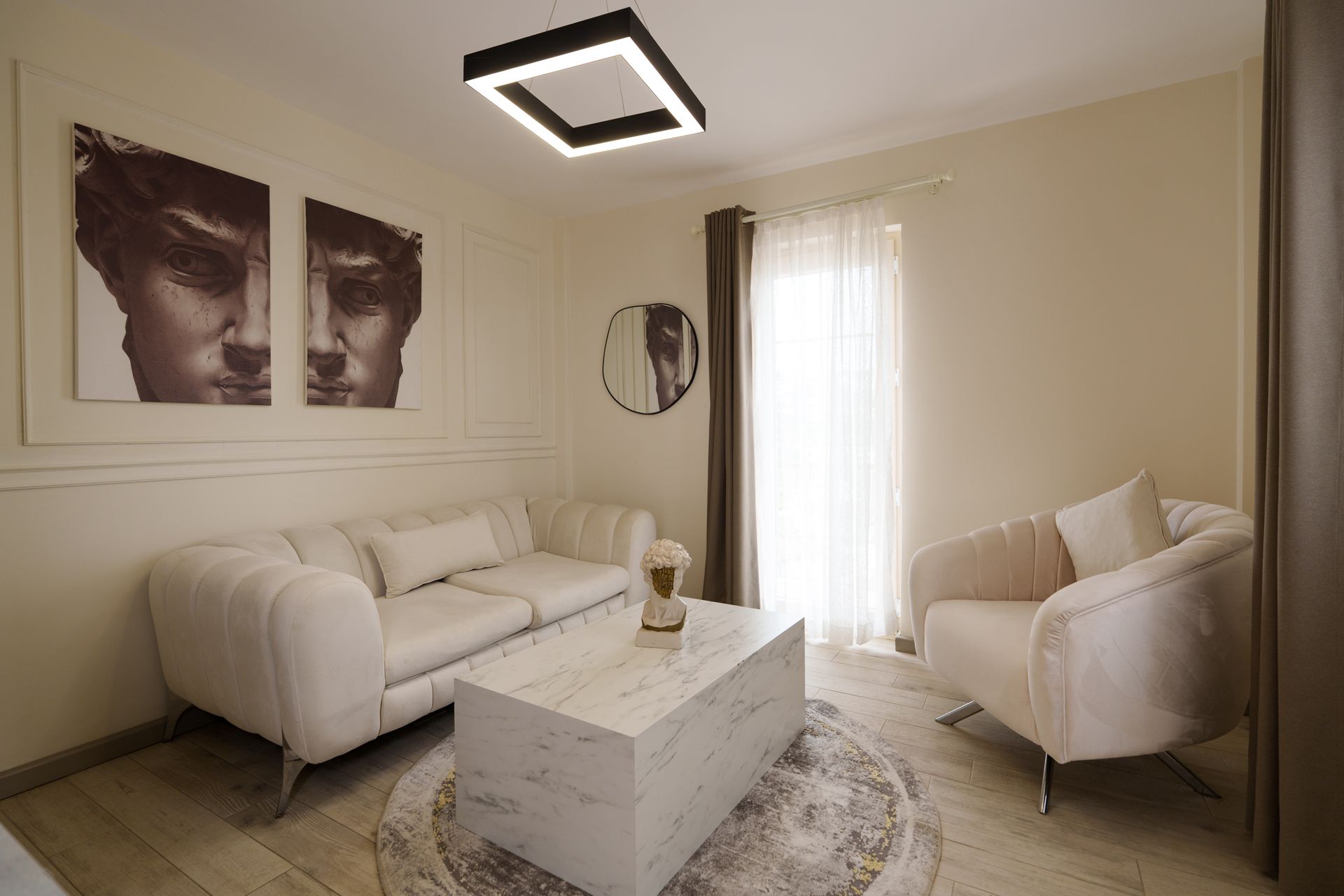 Elemanta Boutique Hotel | Modern beige living room with white sofa and chair, marble coffee table, abstract wall art