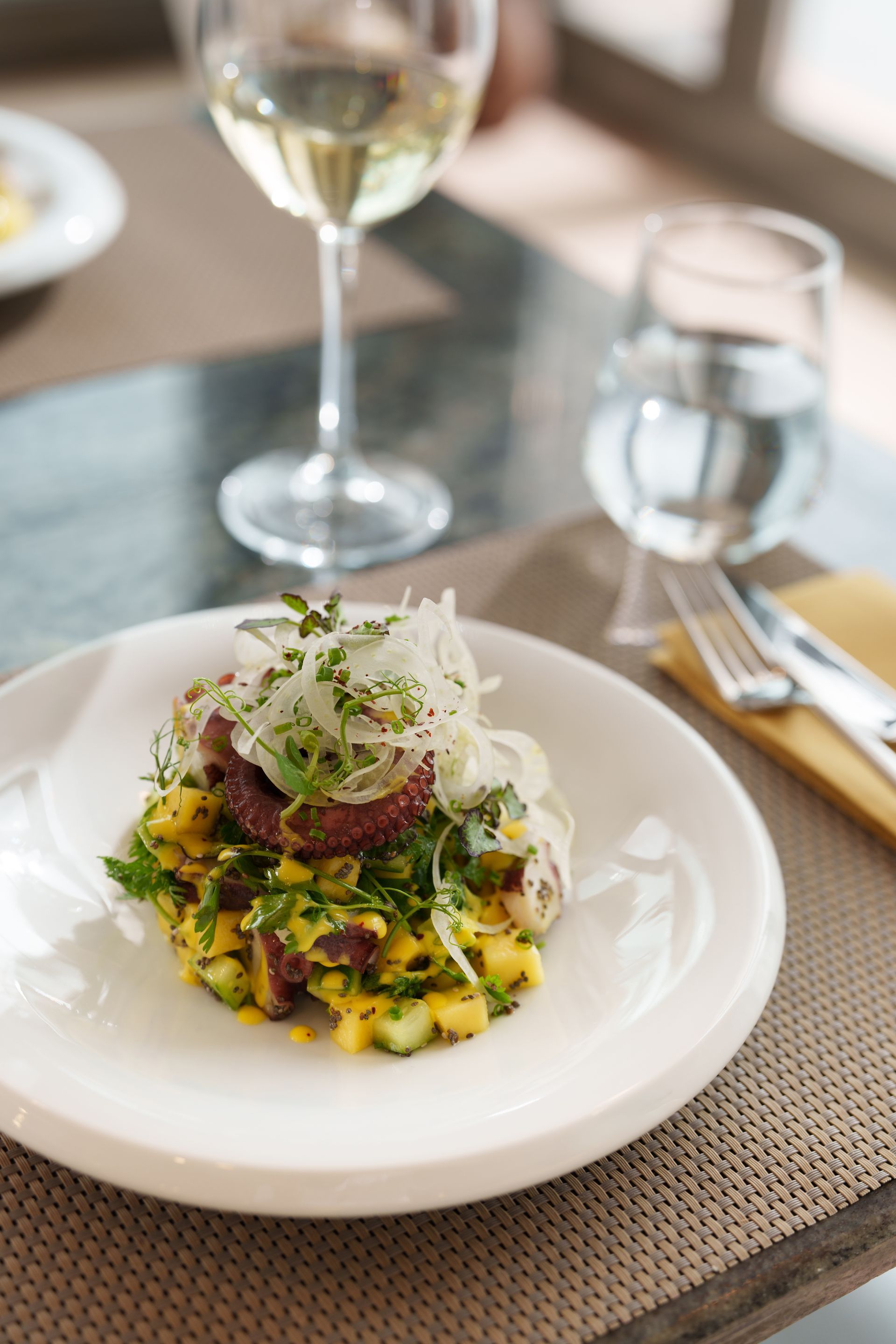 Elemanta Boutique Hotel |Gourmet plated dish topped with microgreens on a restaurant table beside a wine glass