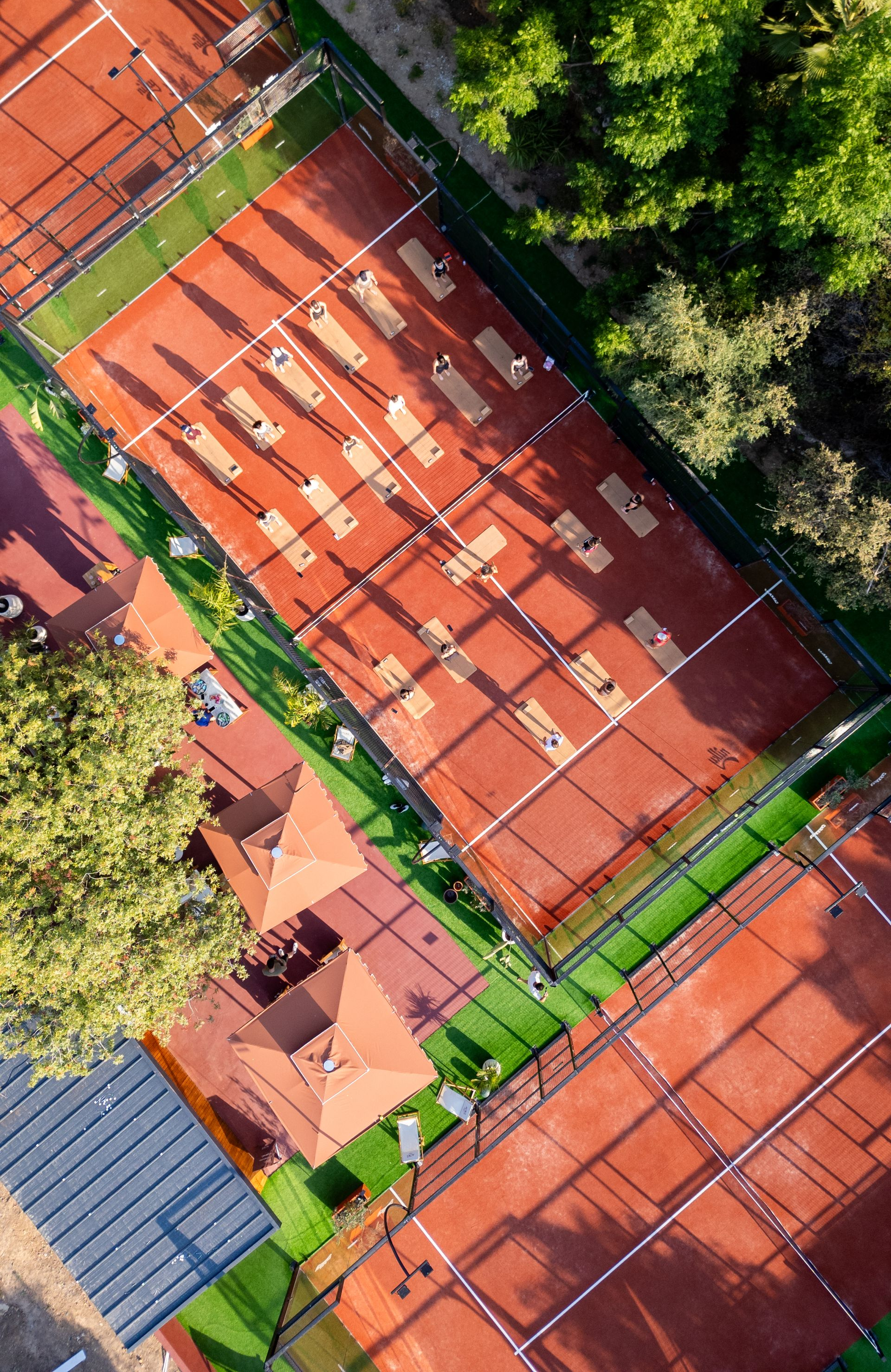 Elemanta Boutique Hotel | Aerial view of orange clay tennis courts beside trees and buildings