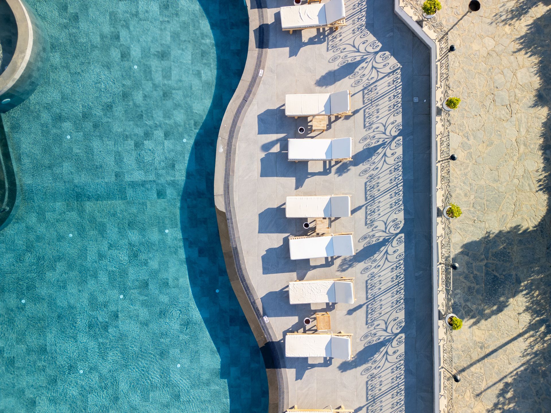 Elemanta Boutique Hotel | Overhead view of a pool with lounge chairs and umbrellas beside turquoise water.