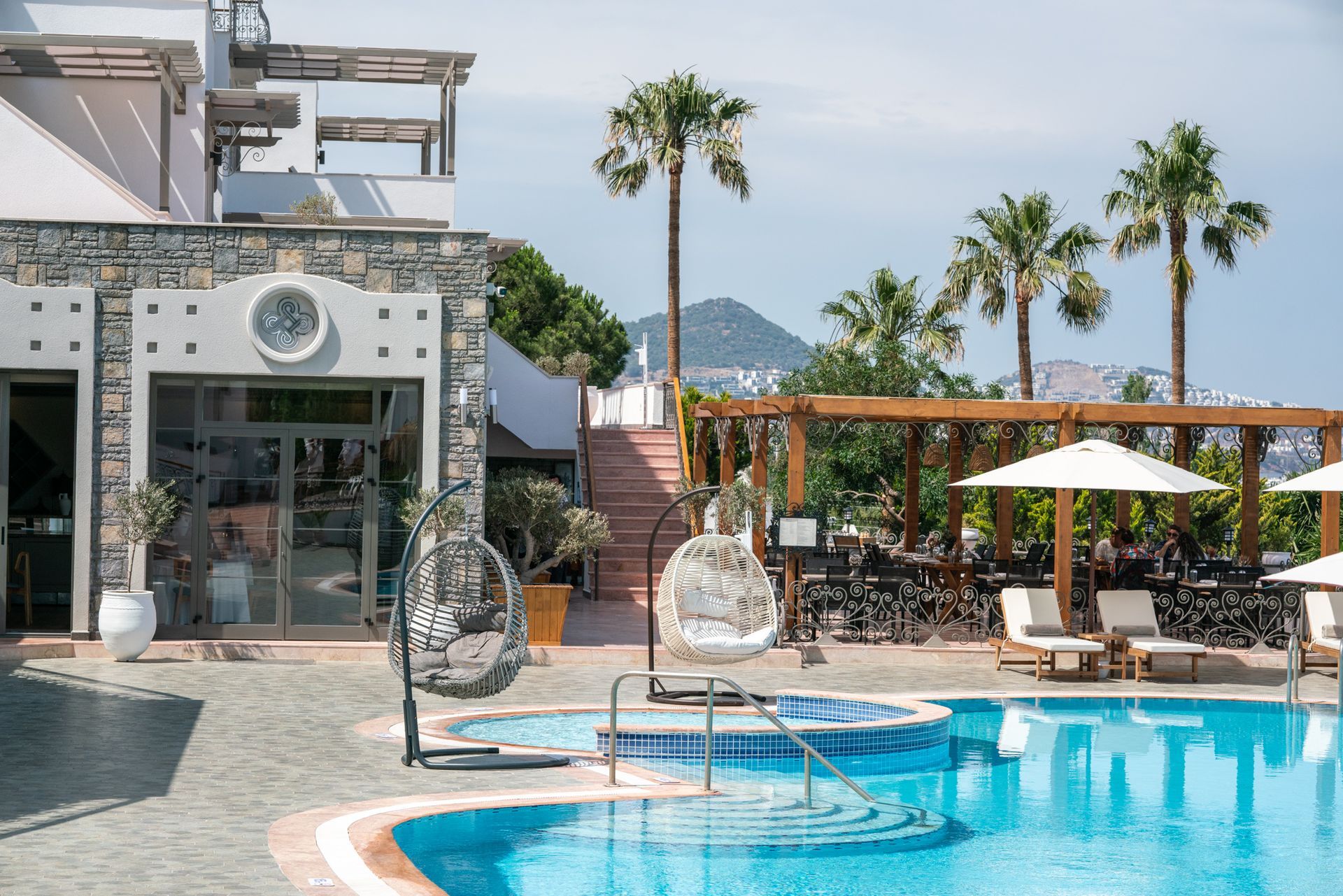  Elemanta Boutique Hotel | Resort pool with lounge chairs, cabanas, and palm trees under a bright blue sky