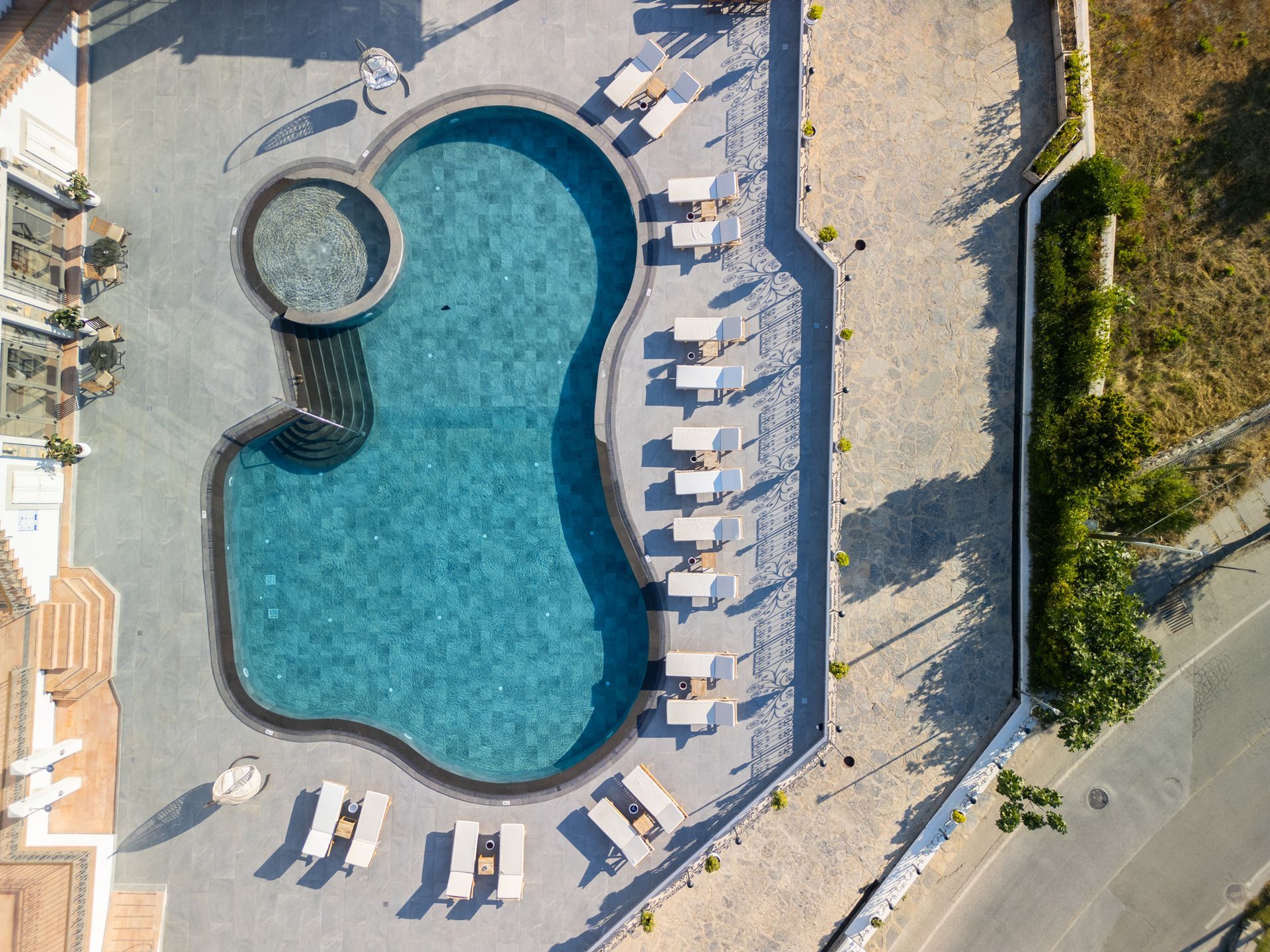  Elemanta Boutique Hotel |  Aerial view of a kidney-shaped swimming pool with lounge chairs on a sunlit patio.