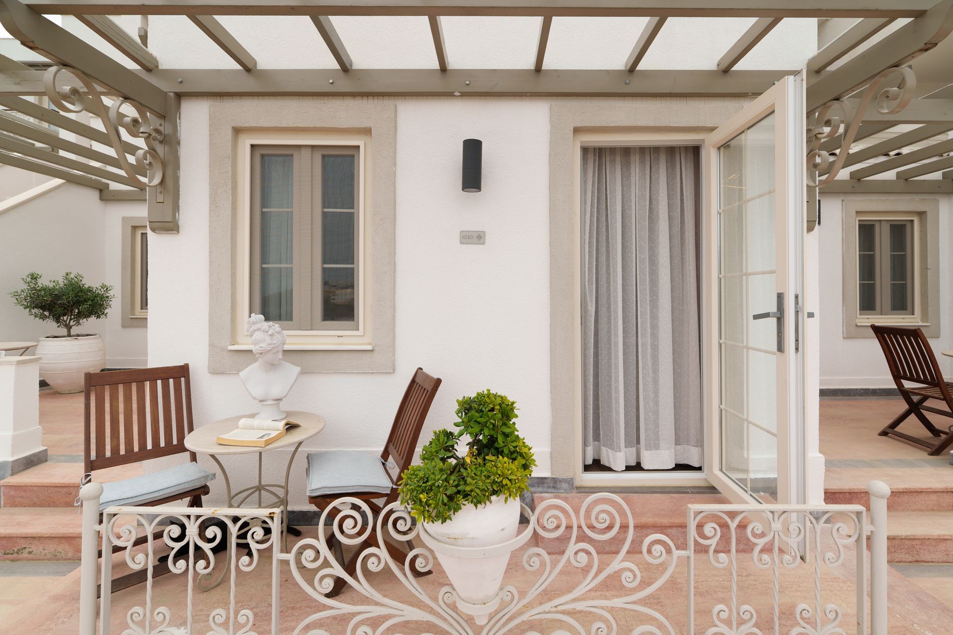  Elemanta Boutique Hotel |  Patio with white doors, small table and chairs, potted plants, and ornate railing under a pergola