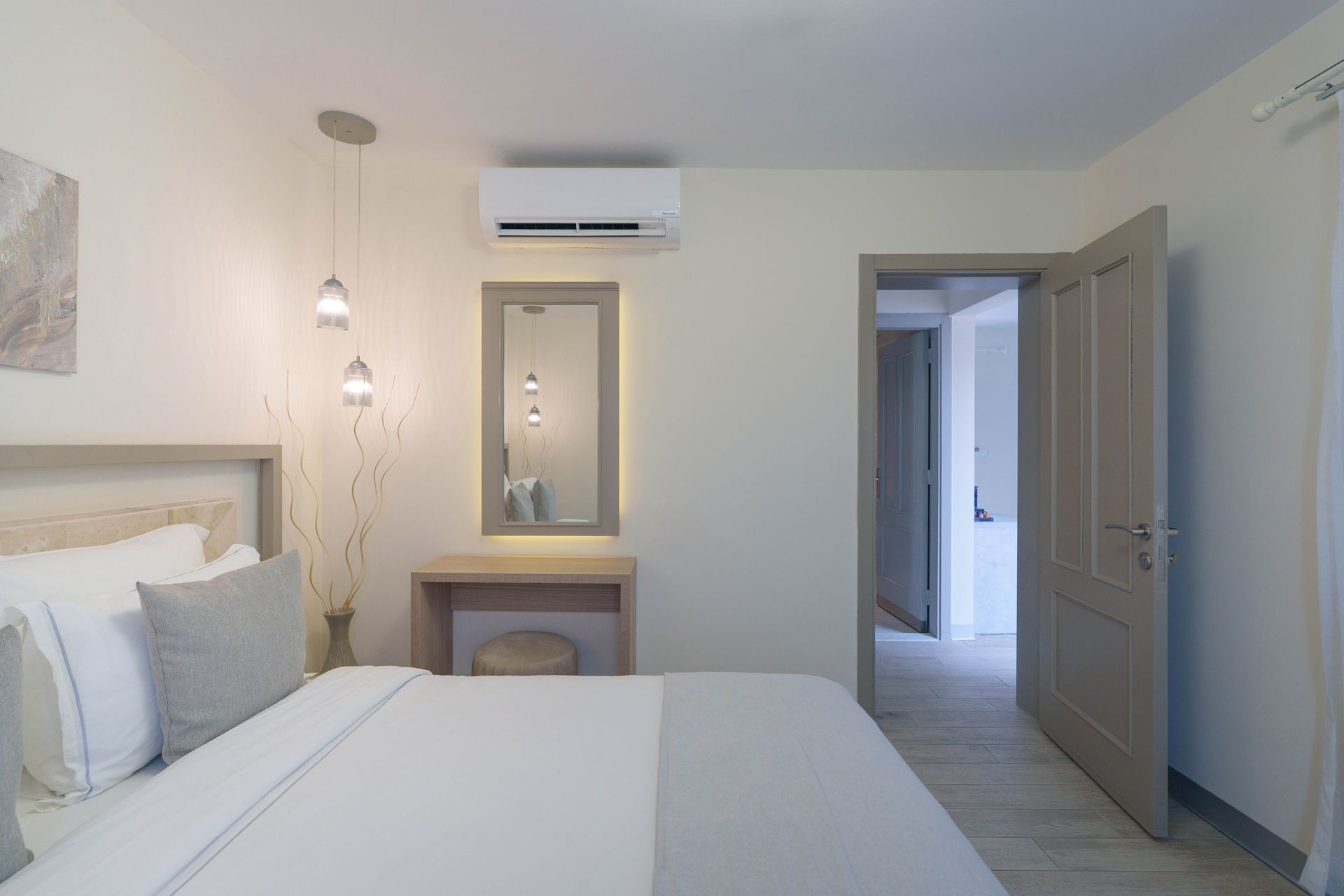 Elemanta Boutique Hotel | Minimal white bedroom with twin beds, vanity mirror, wall-mounted air conditioner
