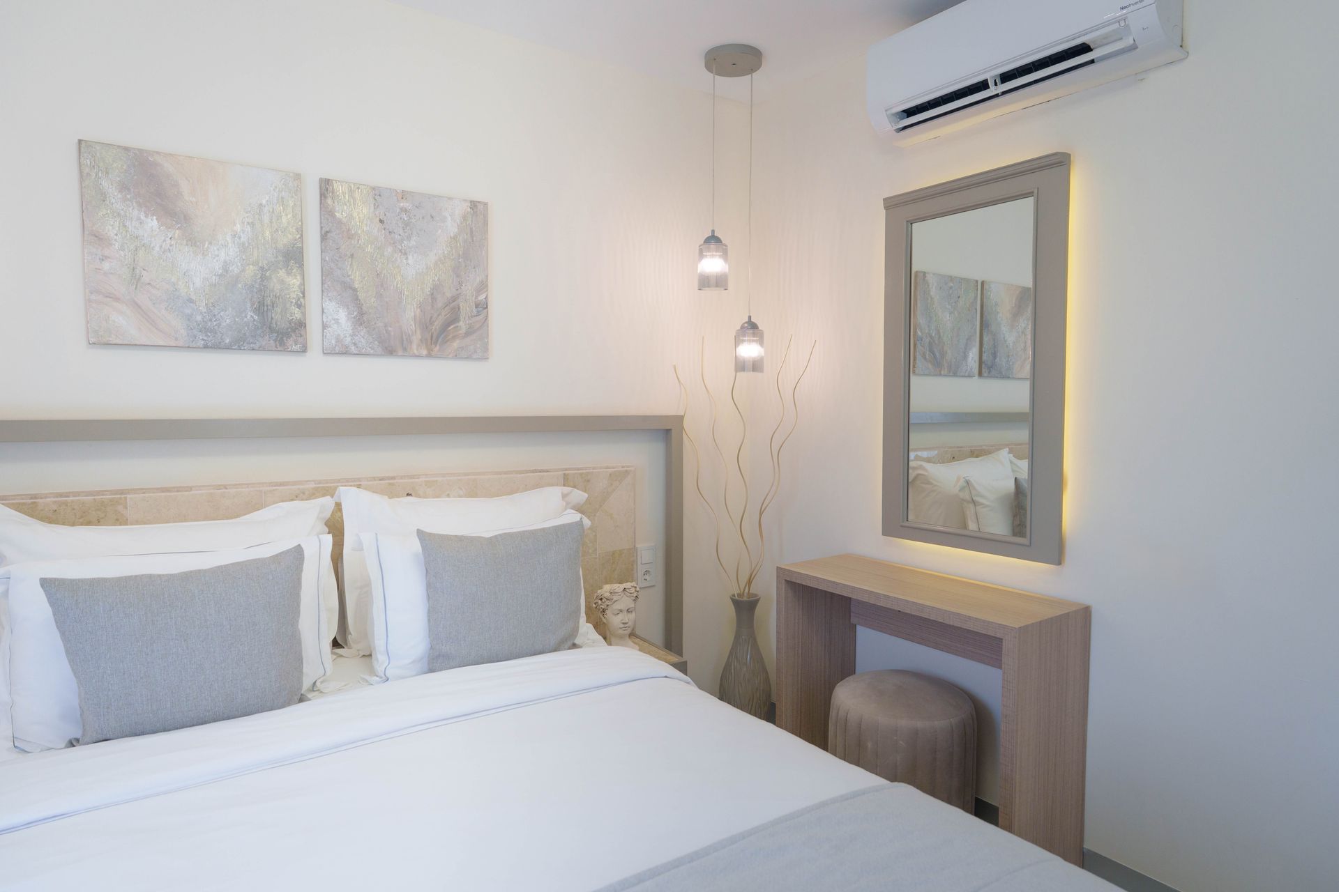 Elemanta Boutique Hotel | Bright minimalist bedroom with white bed, gray pillows, wall art, mirror