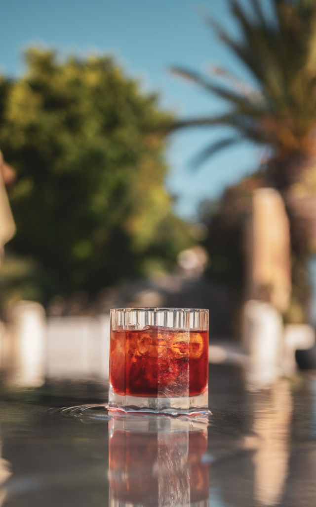 Elemanta Boutique Hotel | A glass of red iced drink on a reflective table with blurred trees
