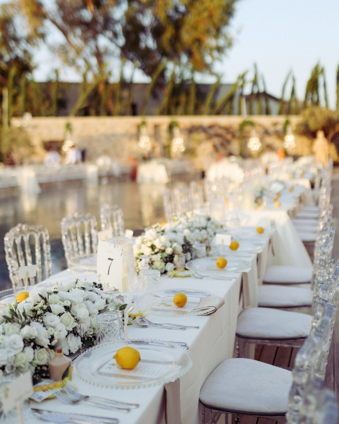 Elemanta Boutique Hotel |Elegant outdoor banquet table set with white flowers, candles, and yellow lemons in a garden setting