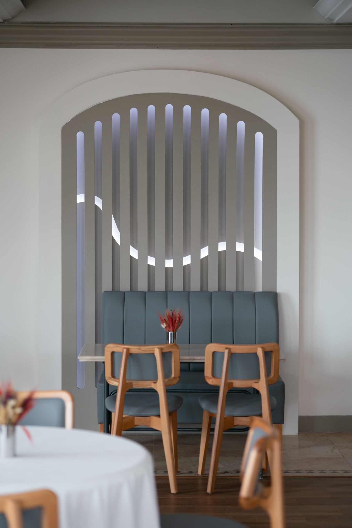 Elemanta Boutique Hotel | Cozy café corner with blue chairs, wooden stools, and arched window slats against a white wall