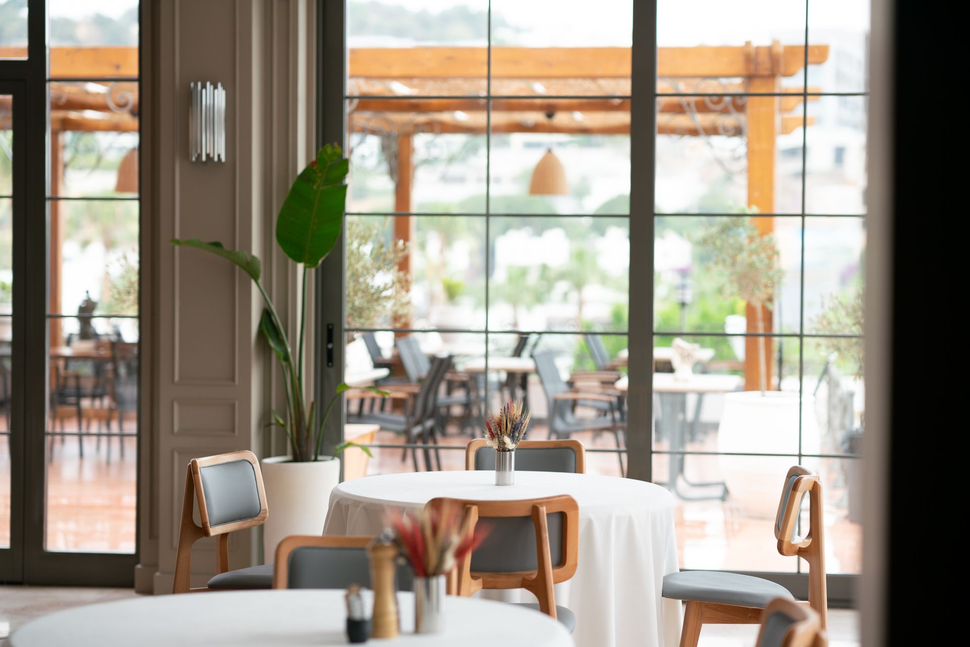  Elemanta Boutique Hotel |  Bright cafe interior with wooden tables, chairs, and large windows opening to a sunny patio