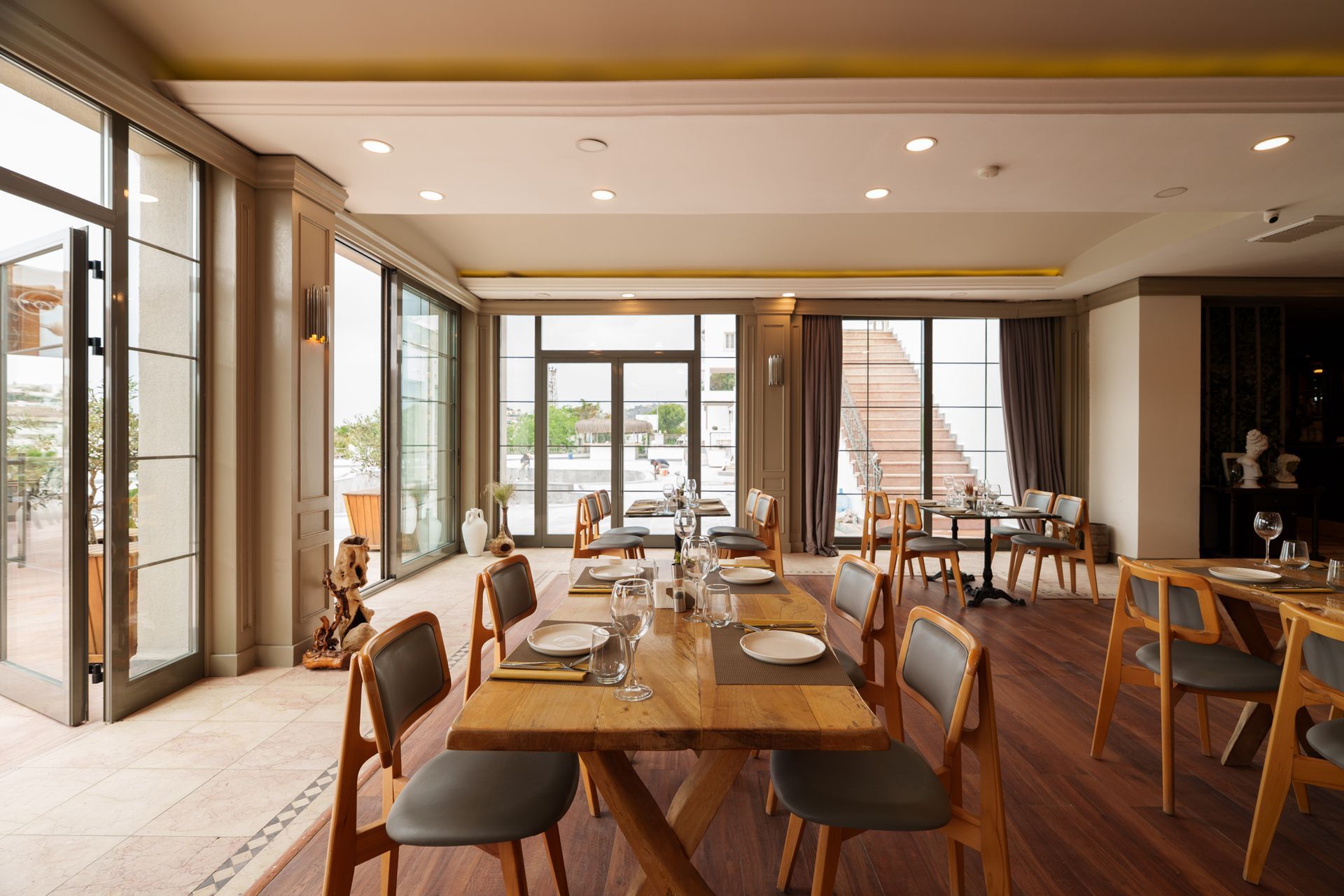  Elemanta Boutique Hotel | Bright modern dining room with wooden tables, chairs, and large windows overlooking greenery.
