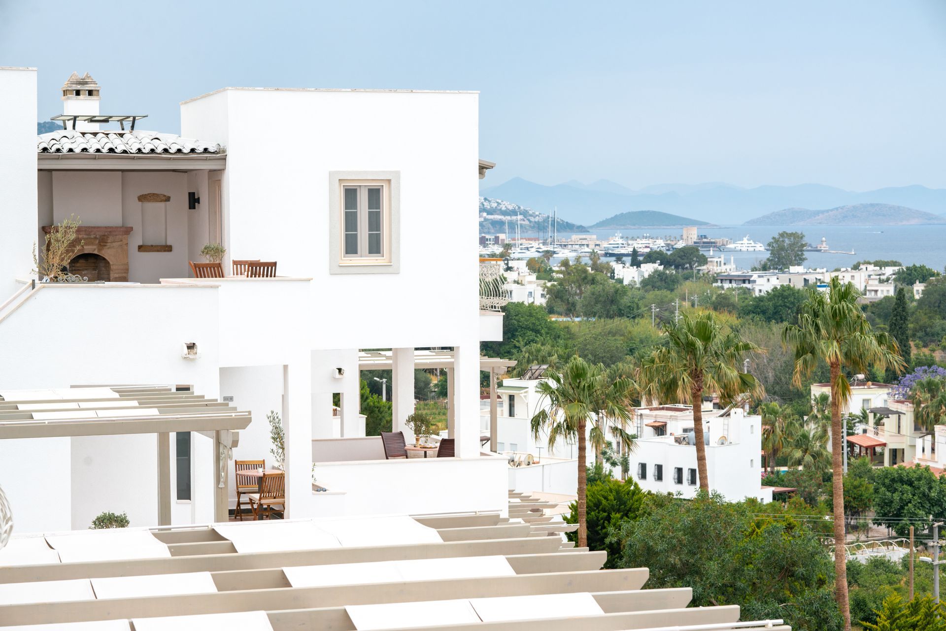  Elemanta Boutique Hotel |  White coastal villa with terraces, palm trees, and a hazy blue sea view in the background