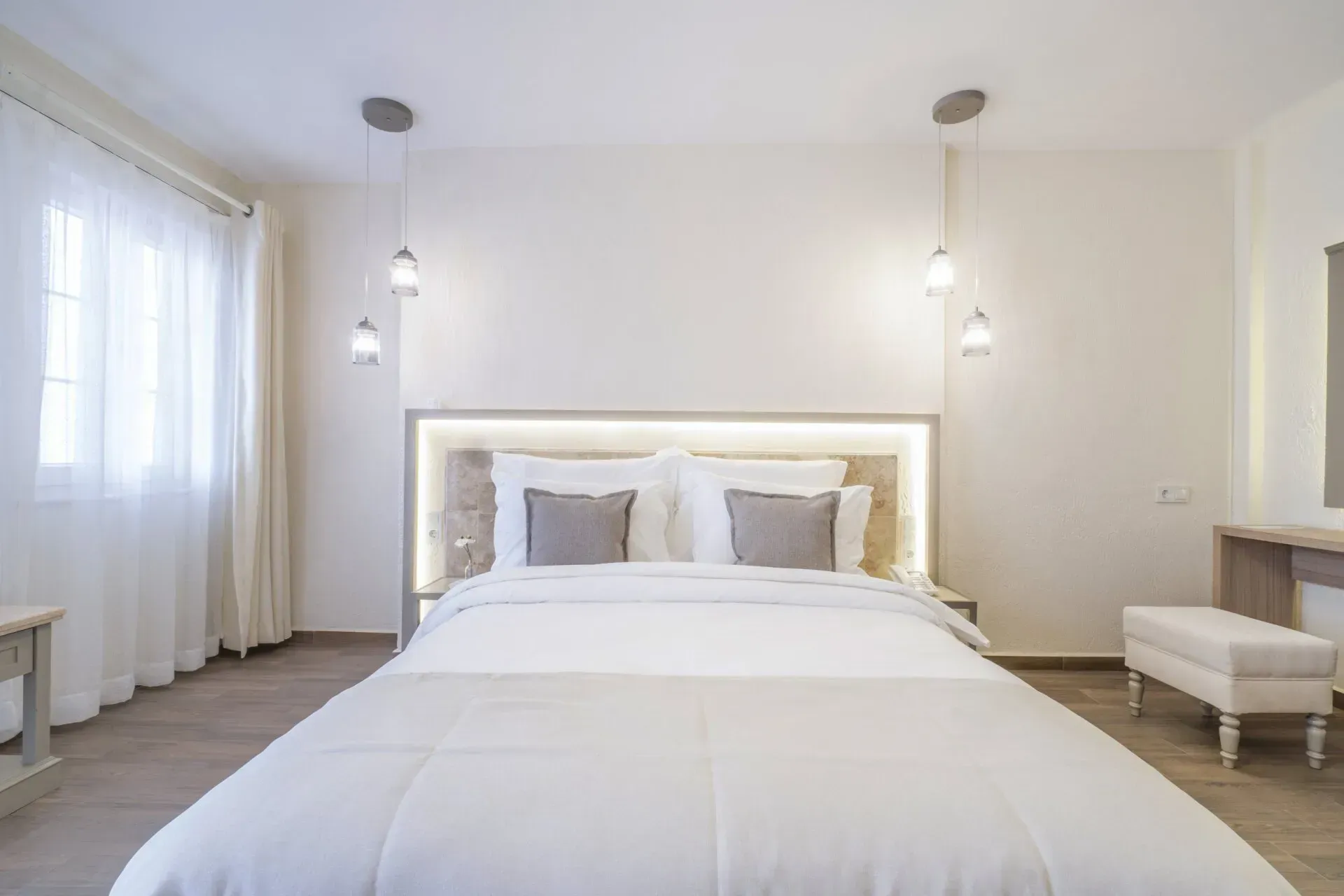  Elemanta Boutique Hotel |  Bright white minimalist bedroom with a large bed, pendant lights, sheer curtains