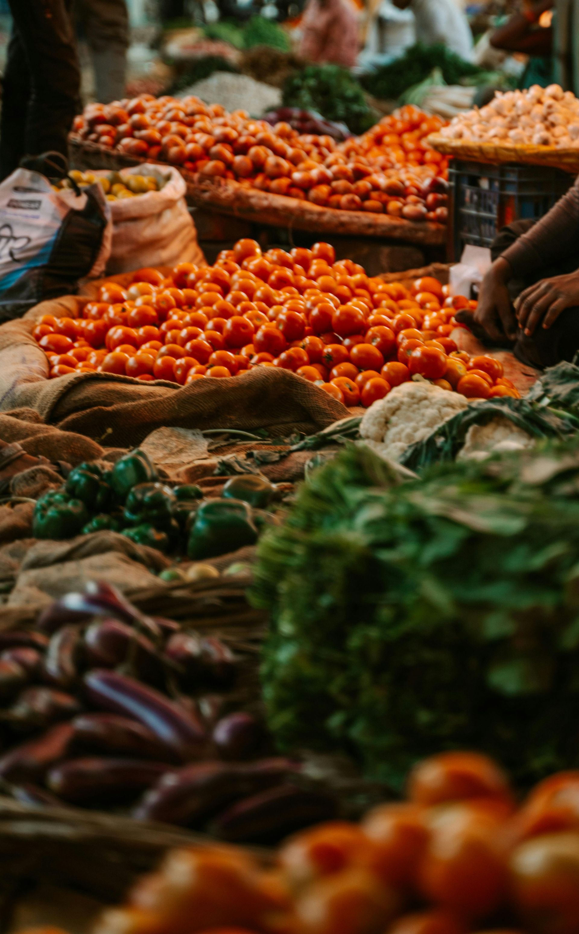 Elemanta Boutique Hotel | Market stall piled with red tomatoes, green vegetables, and produce in woven baskets