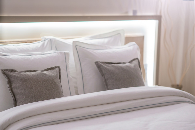 Elemanta Boutique Hotel | White bed with neatly made pillows and gray accent cushions in a softly lit bedroom
