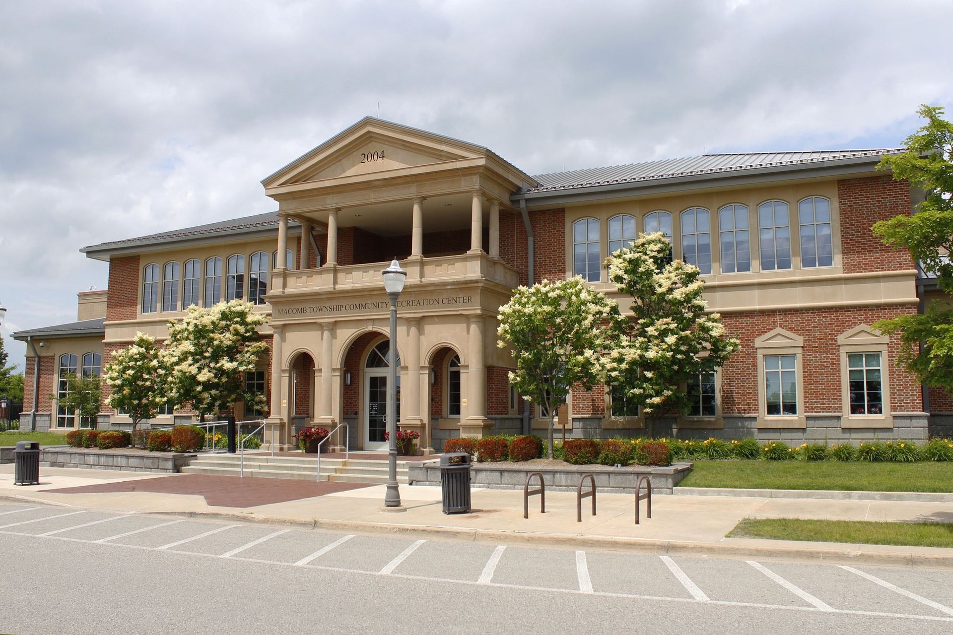 Historic brick civic building with a columned entrance and arched windows on a quiet street