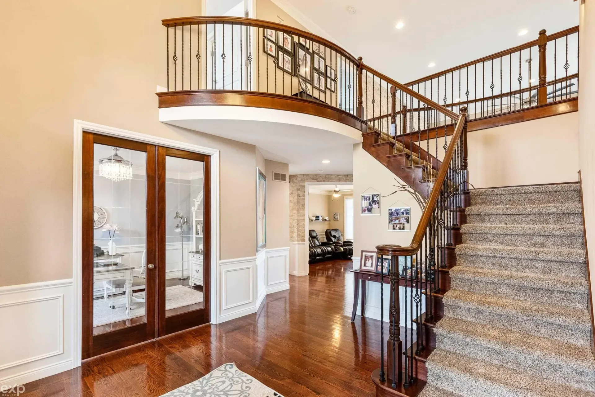 Bright foyer with curved staircase, hardwood floors, white walls, and glass double doors