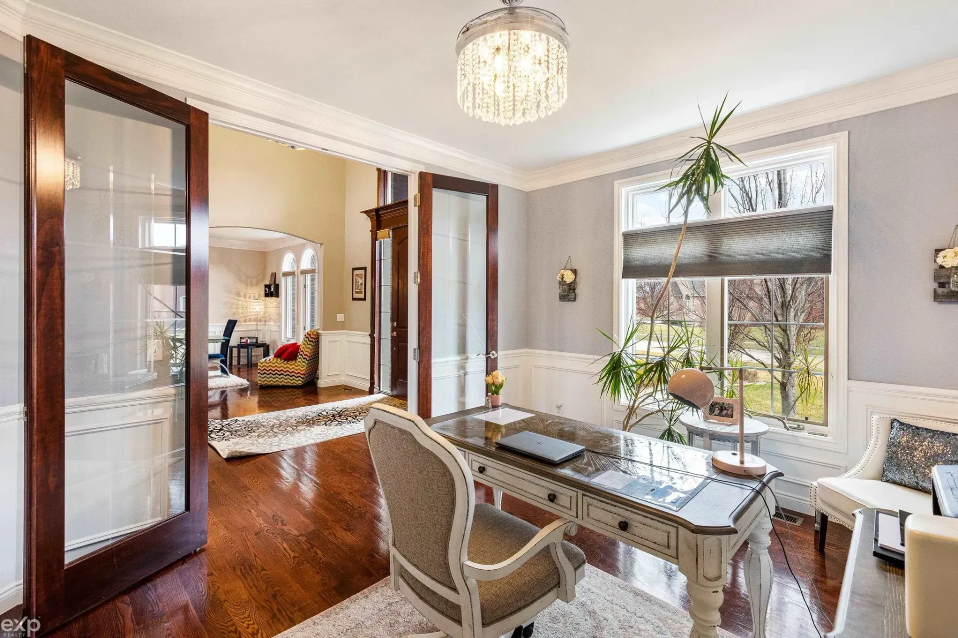 Elegant dining room with chandelier, wooden floor, and a window bench by a bright window