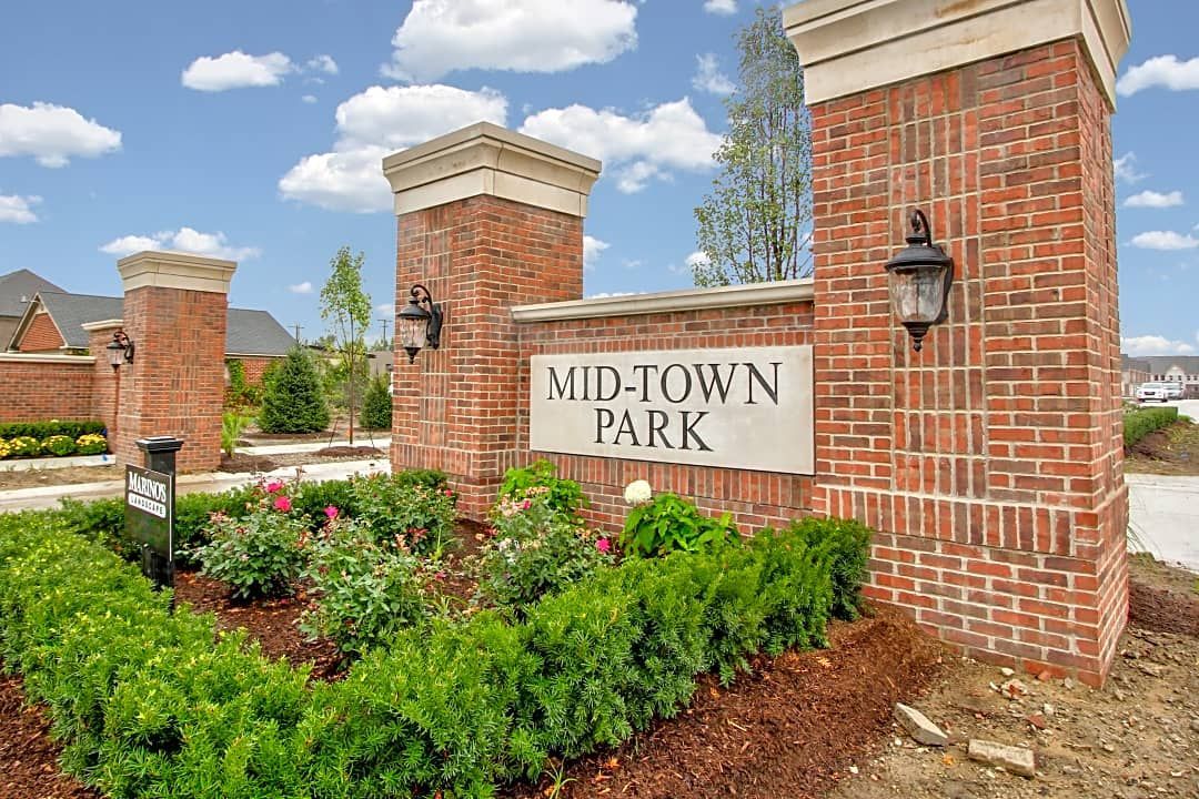 Brick entrance sign reading “WIL-TOWN PARK” beside flowers and brick pillars under a blue sky