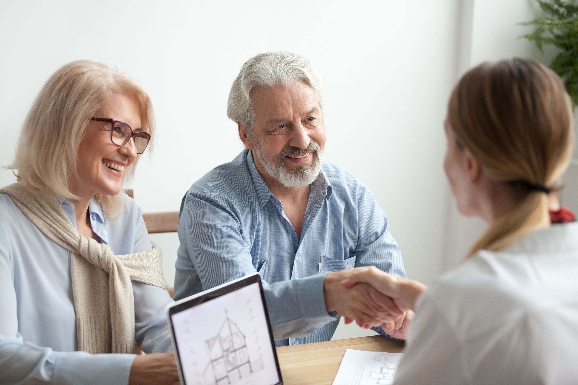 Happy older family and Real Estate Agent shake hands buying new house