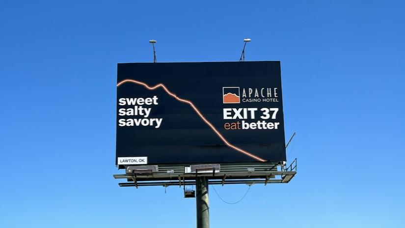 Billboard against blue sky reading “sweet salty savory” and “APACHE EXIT 37 eat better”