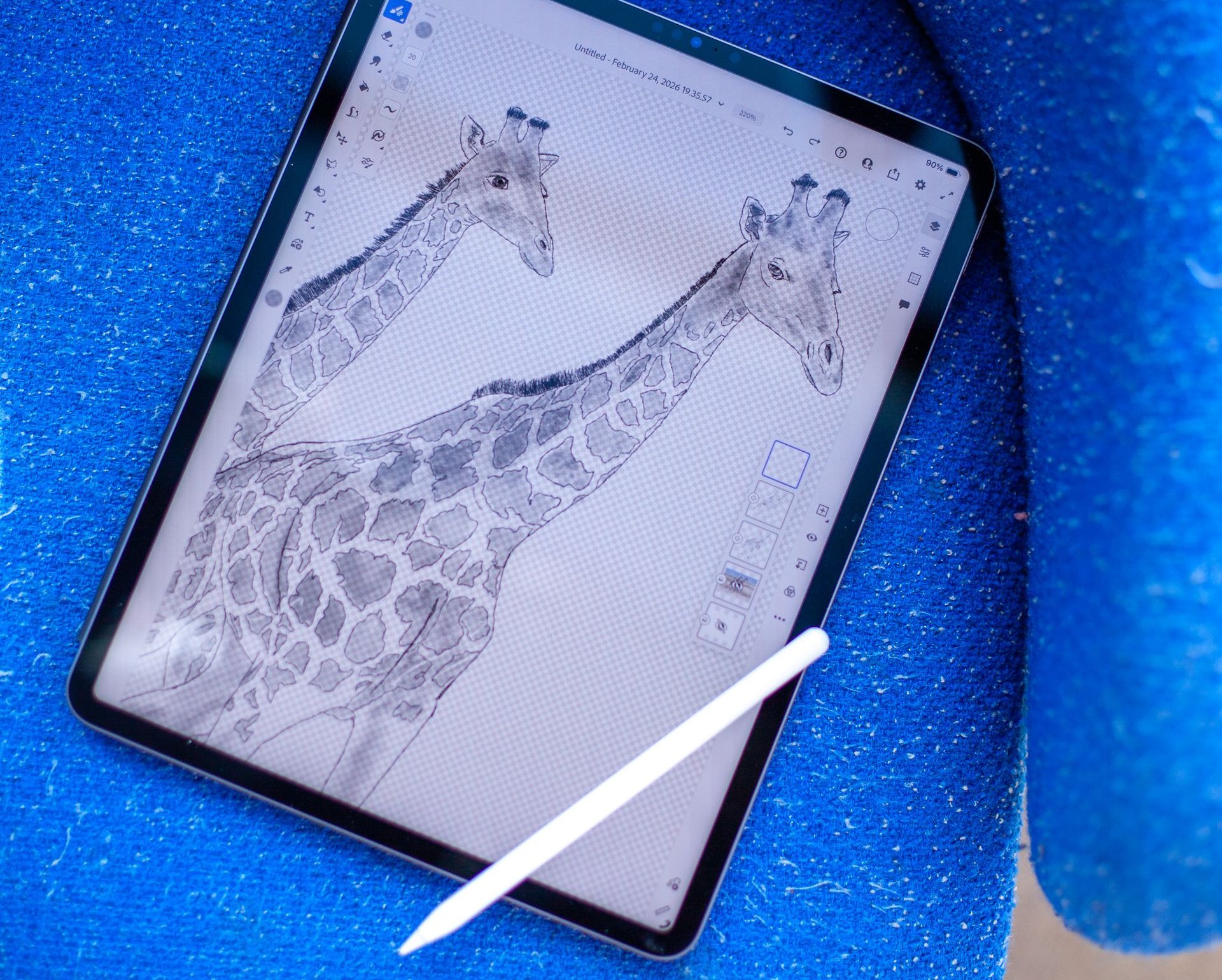 A tablet displaying a giraffe sketch, with a digital pen resting on top, set against a textured blue background.