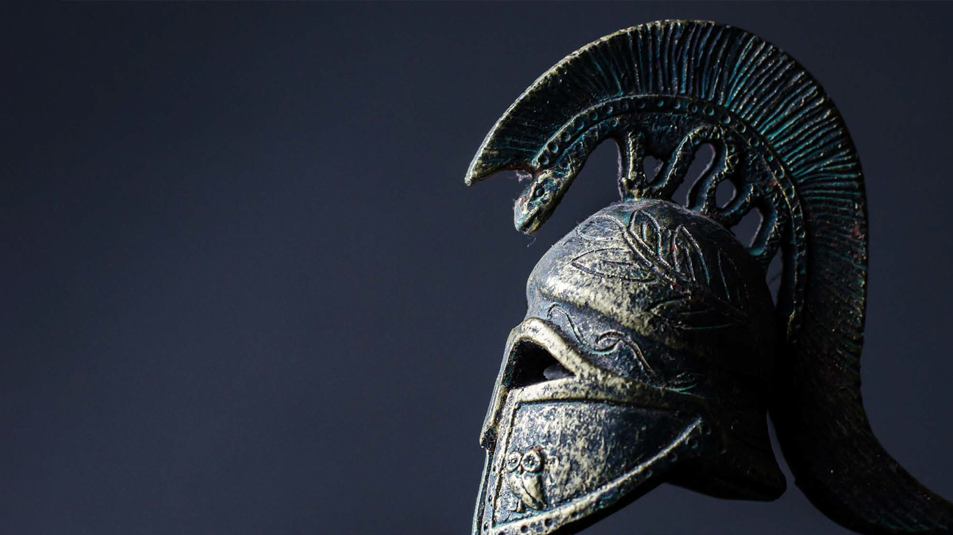 Ancient Greek bronze helmet with horsehair crest, lit against a dark background