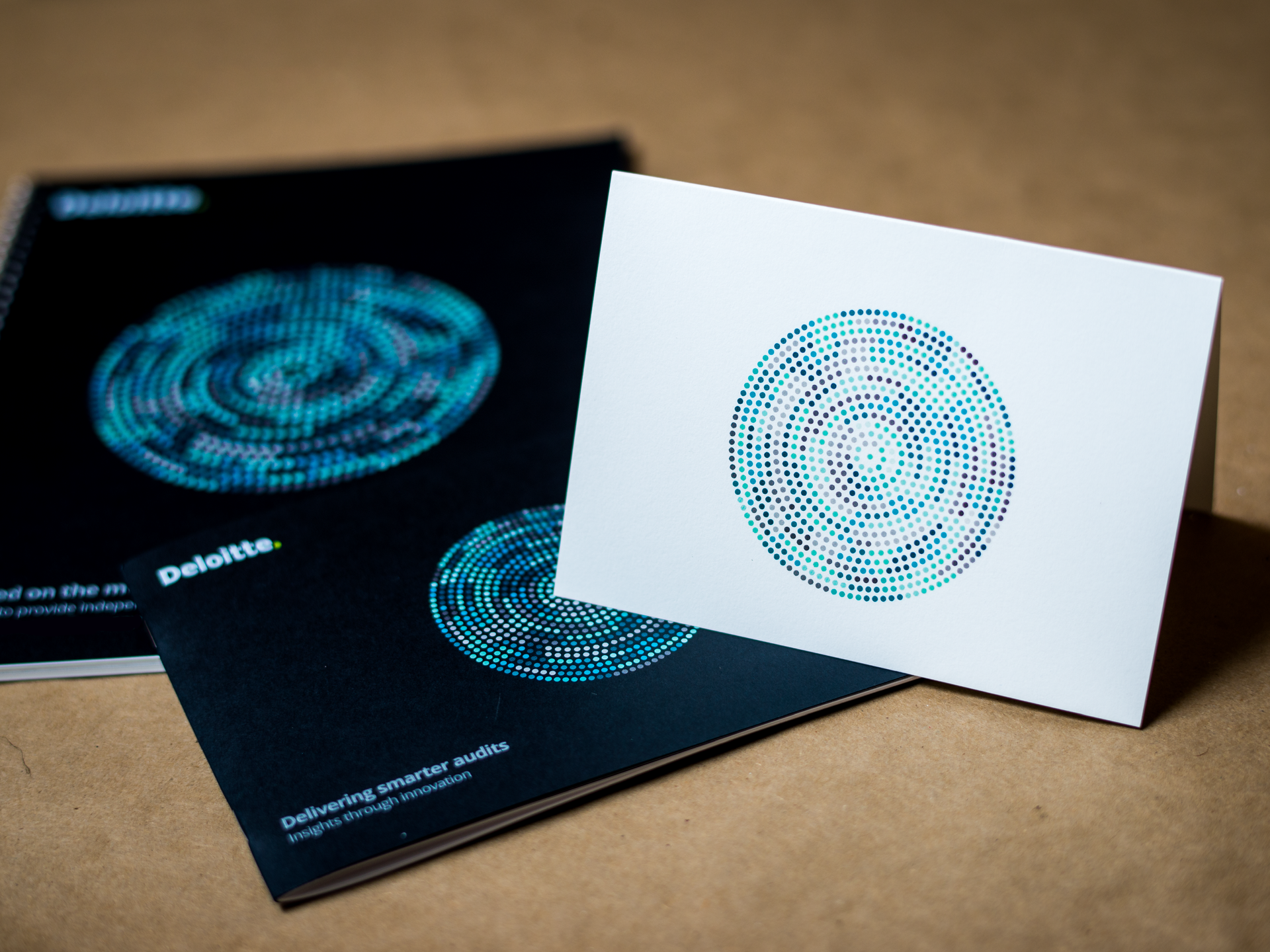 Three black and white design cards with blue circular patterns on a brown surface