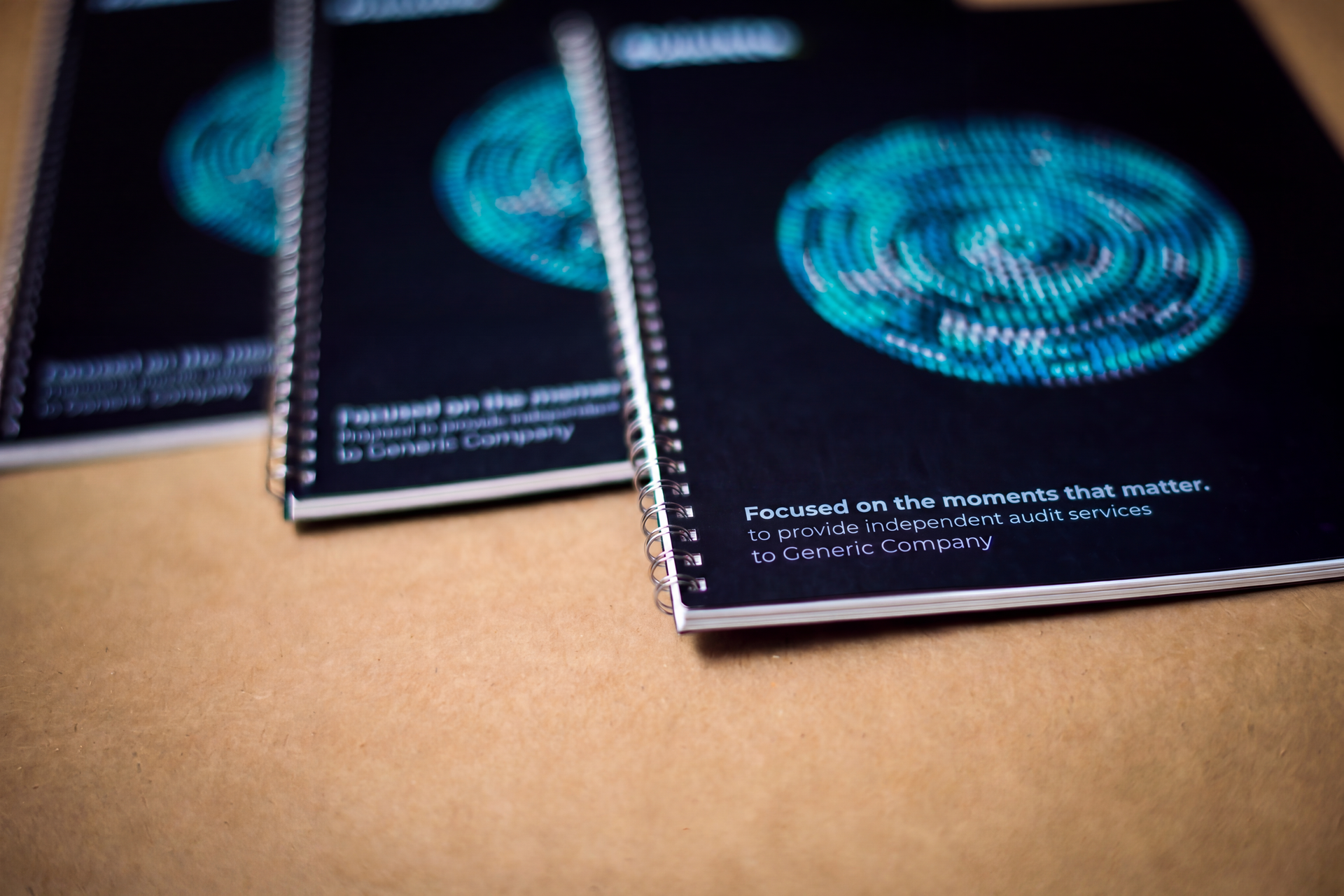 Three black spiral notebooks with blue circular designs on a tan surface