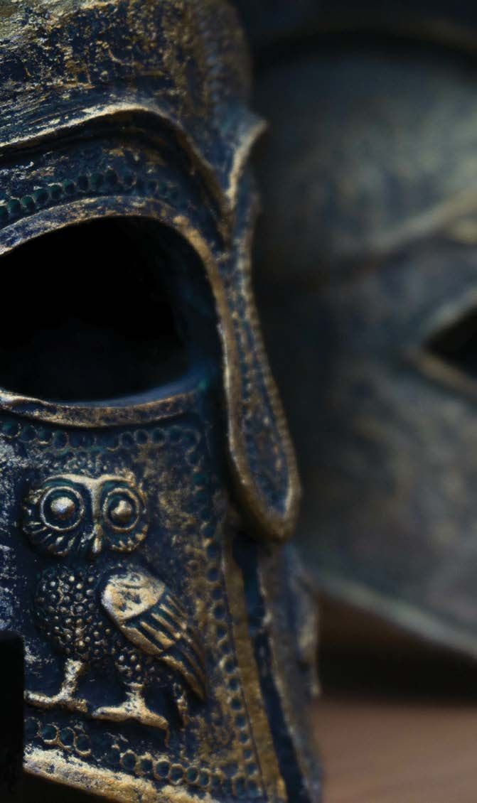 Close-up of two dark blue decorative owl masks, one in sharp focus with a gold owl emblem.