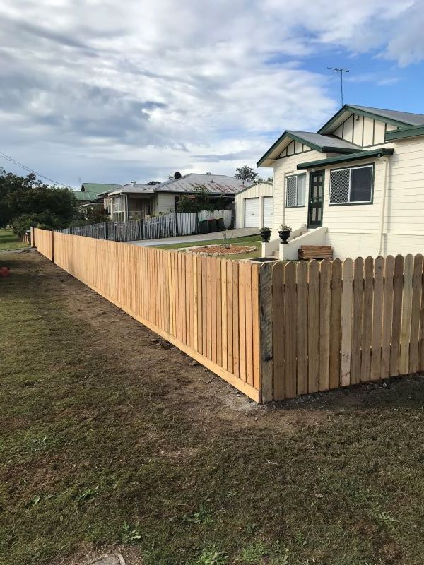 A Long Wooden Fence is in Front of a House — Aztech Fencing In Laurieton, NSW