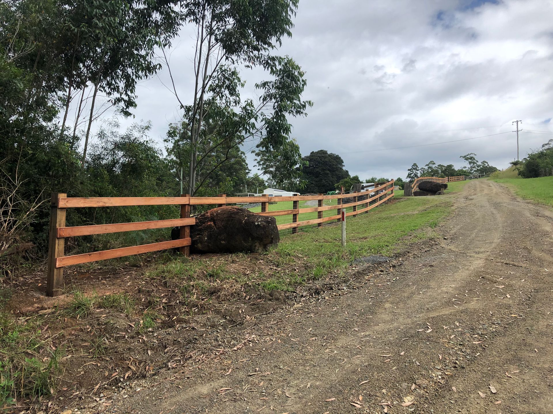 A Wooden Fence With a Brick House in the Background — Aztech Fencing In Port Macquarie, NSW