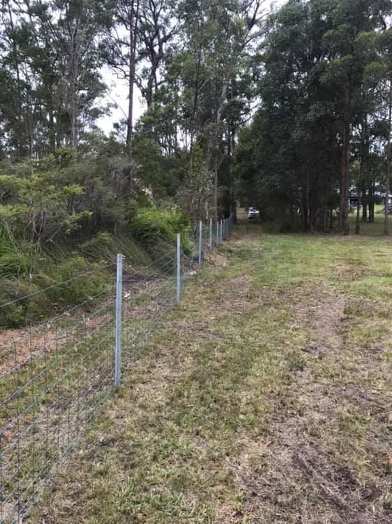 A Fence Surrounds a Grassy Field With Trees in the Background — Aztech Fencing In Upsalls Creek, NSW