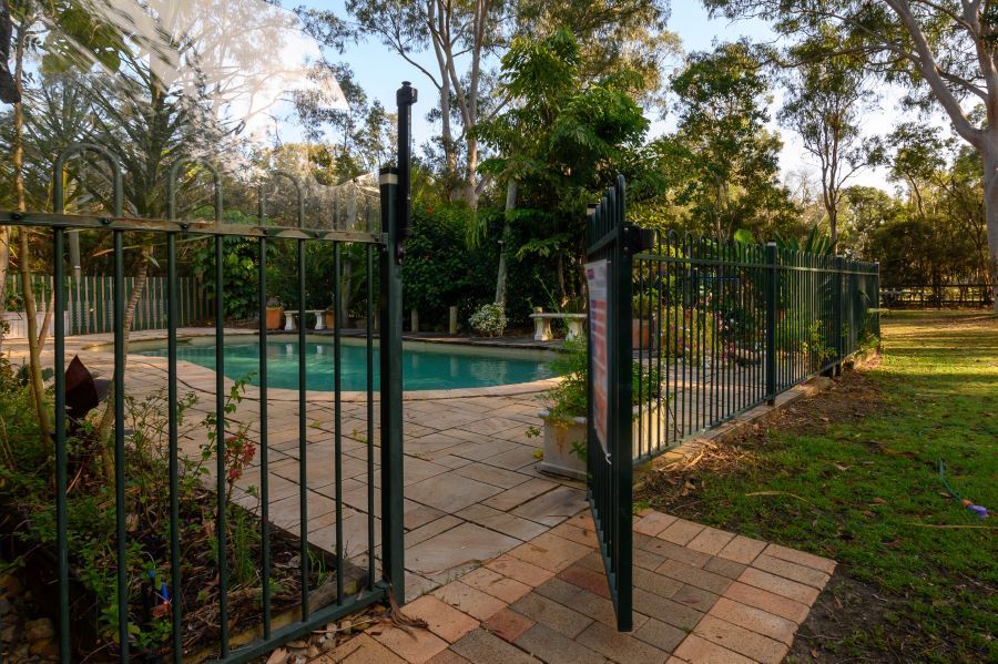 A Fence Surrounds a Swimming Pool in a Backyard — Aztech Fencing In Bonny Hills, NSW