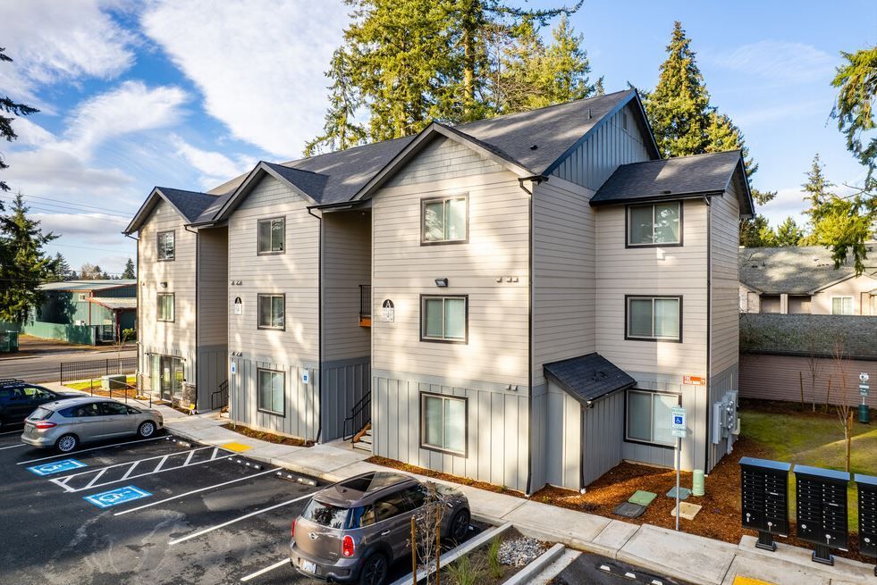 Apartment building exterior with parked cars and a blue accessible parking space