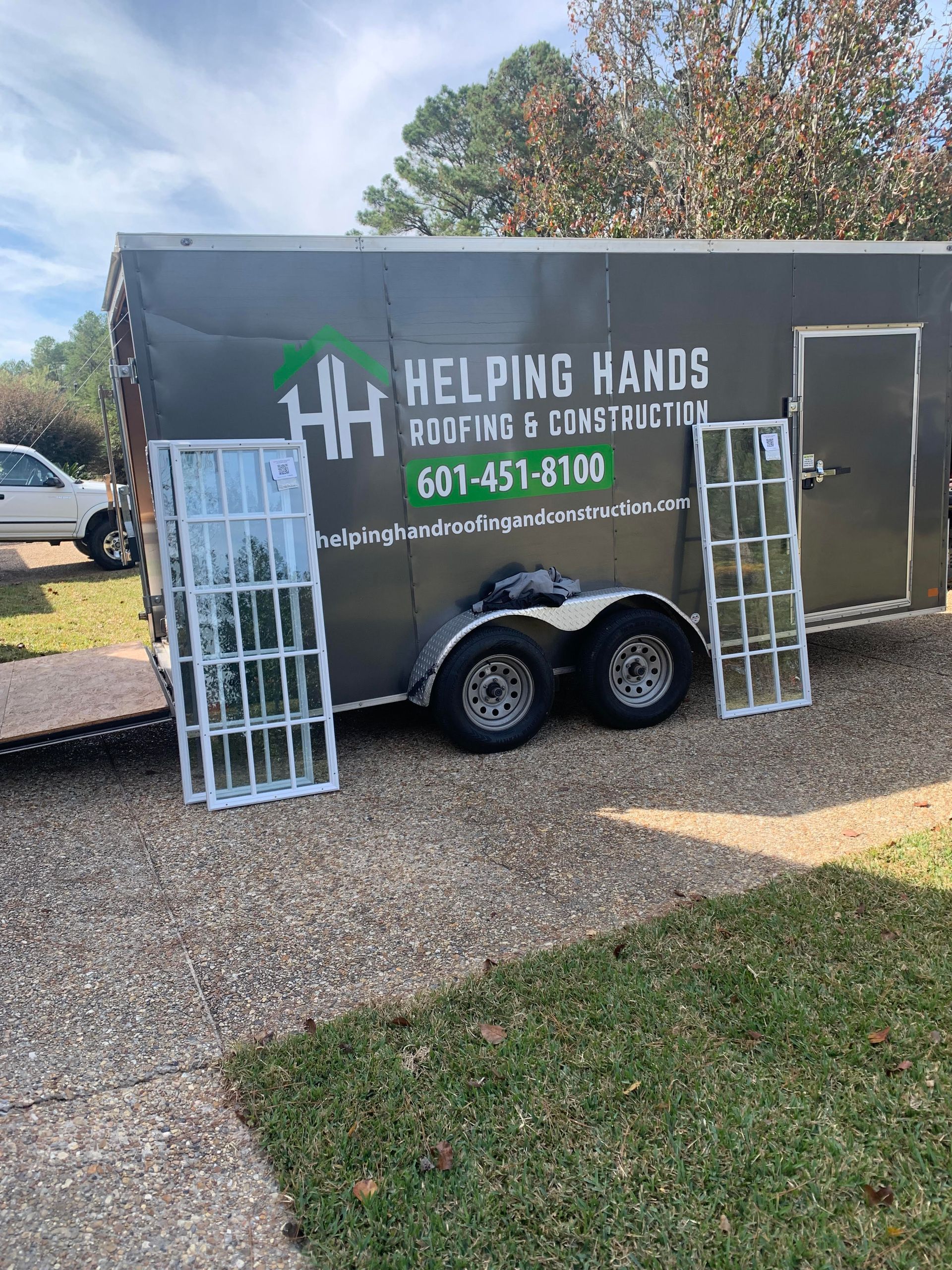 Helping Hands Food & Construction trailer with white racks parked on a gravel driveway outdoors