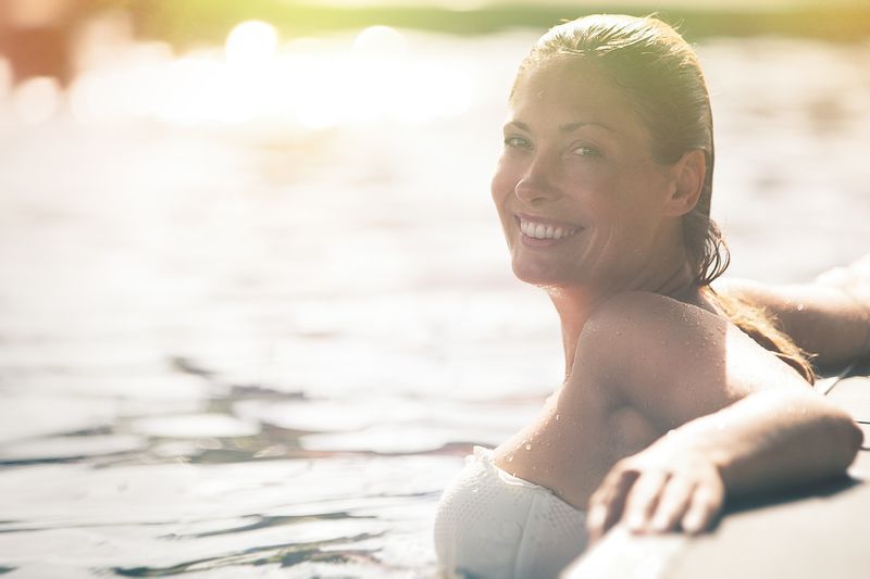 A woman is smiling while laying in the water.