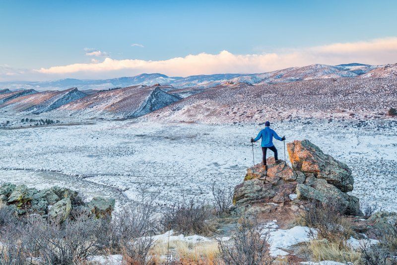 A man is standing on top of a rock in the snow.