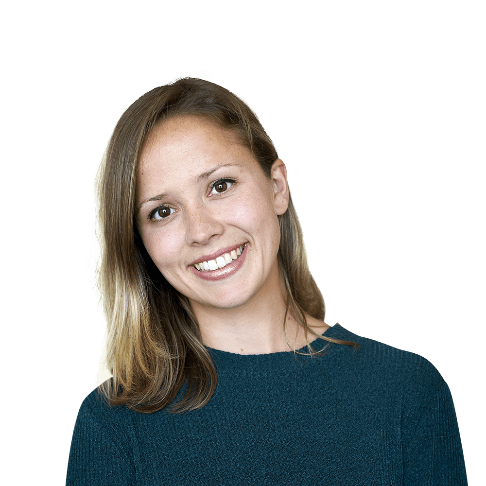 A person with shoulder-length hair wearing a dark teal sweater smiles against a plain white background.