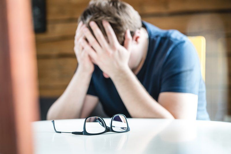 A man is sitting at a table with his head in his hands.