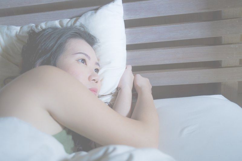 A woman is laying in bed with her head on a pillow.