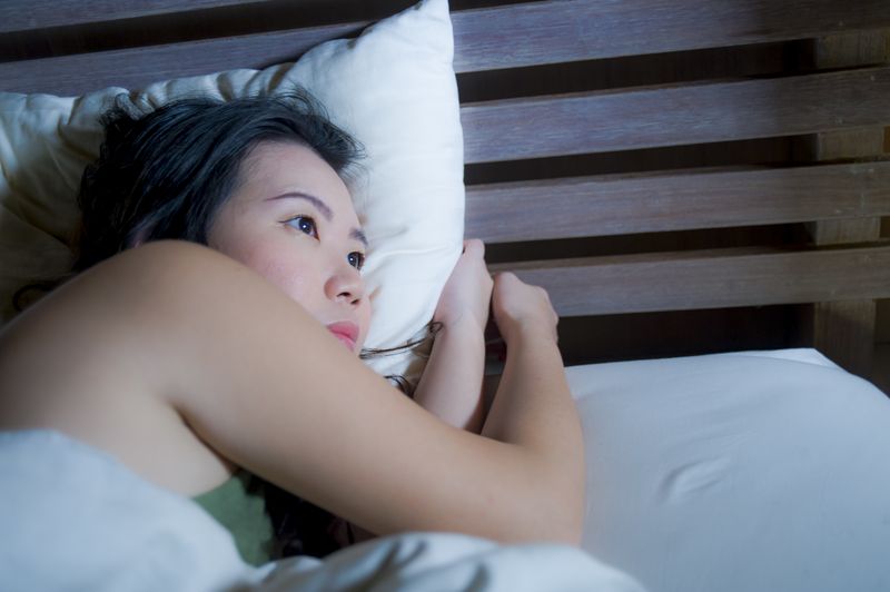 A woman is laying in bed with her head on a pillow.