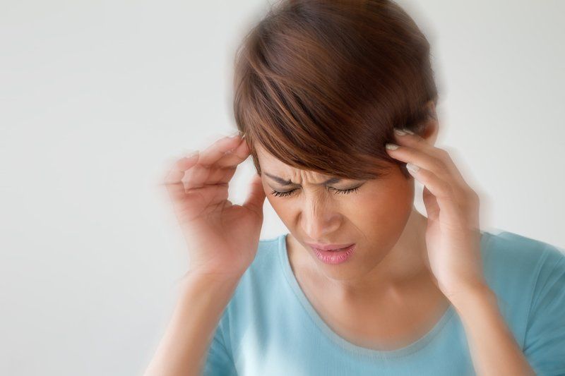A woman is holding her head because she has a headache.