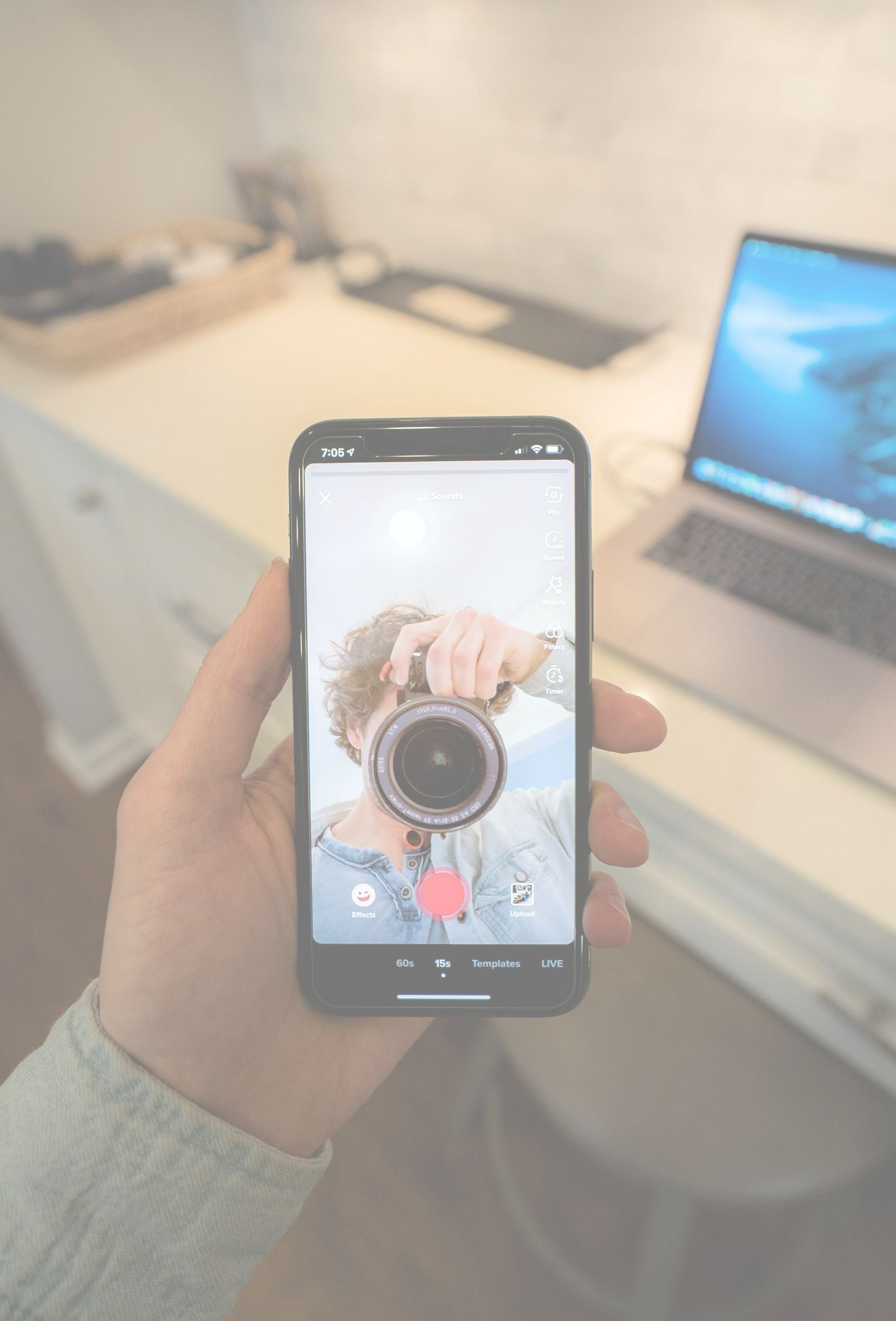 A person is holding a cell phone in their hand and taking a picture of themselves with a camera.
