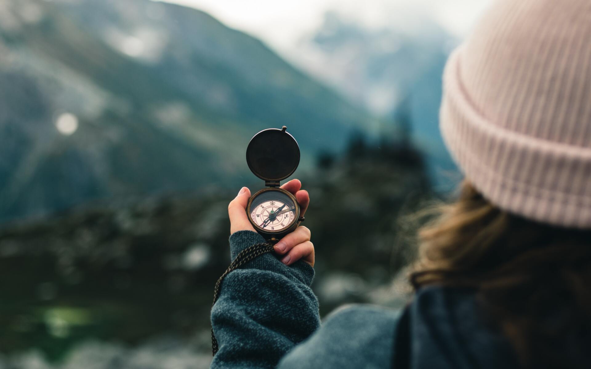 A woman is holding a compass in her hand in front of a mountain.