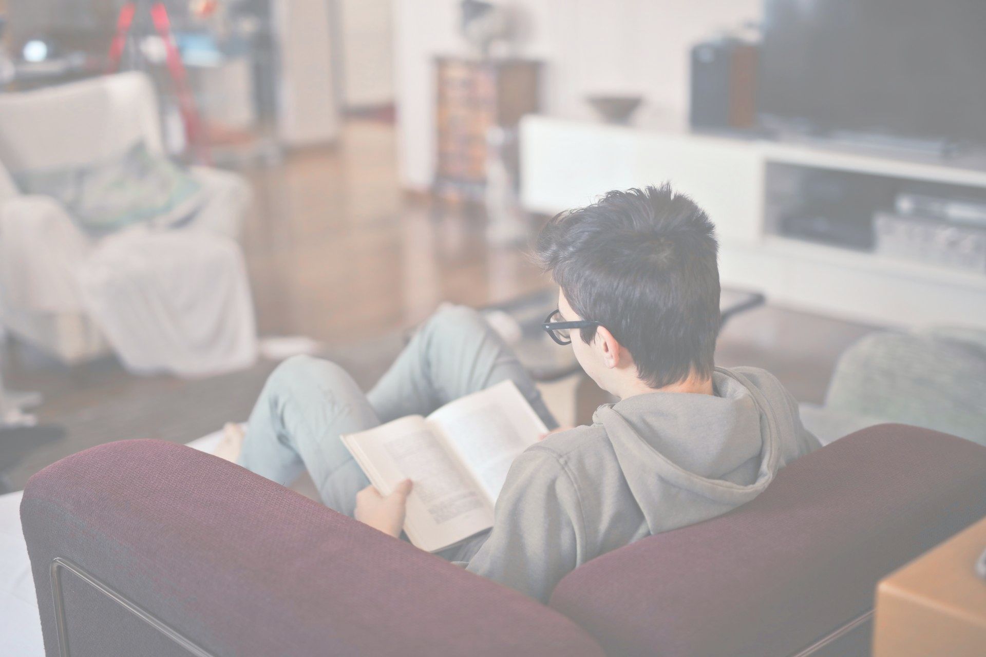 A man is sitting on a couch reading a book.