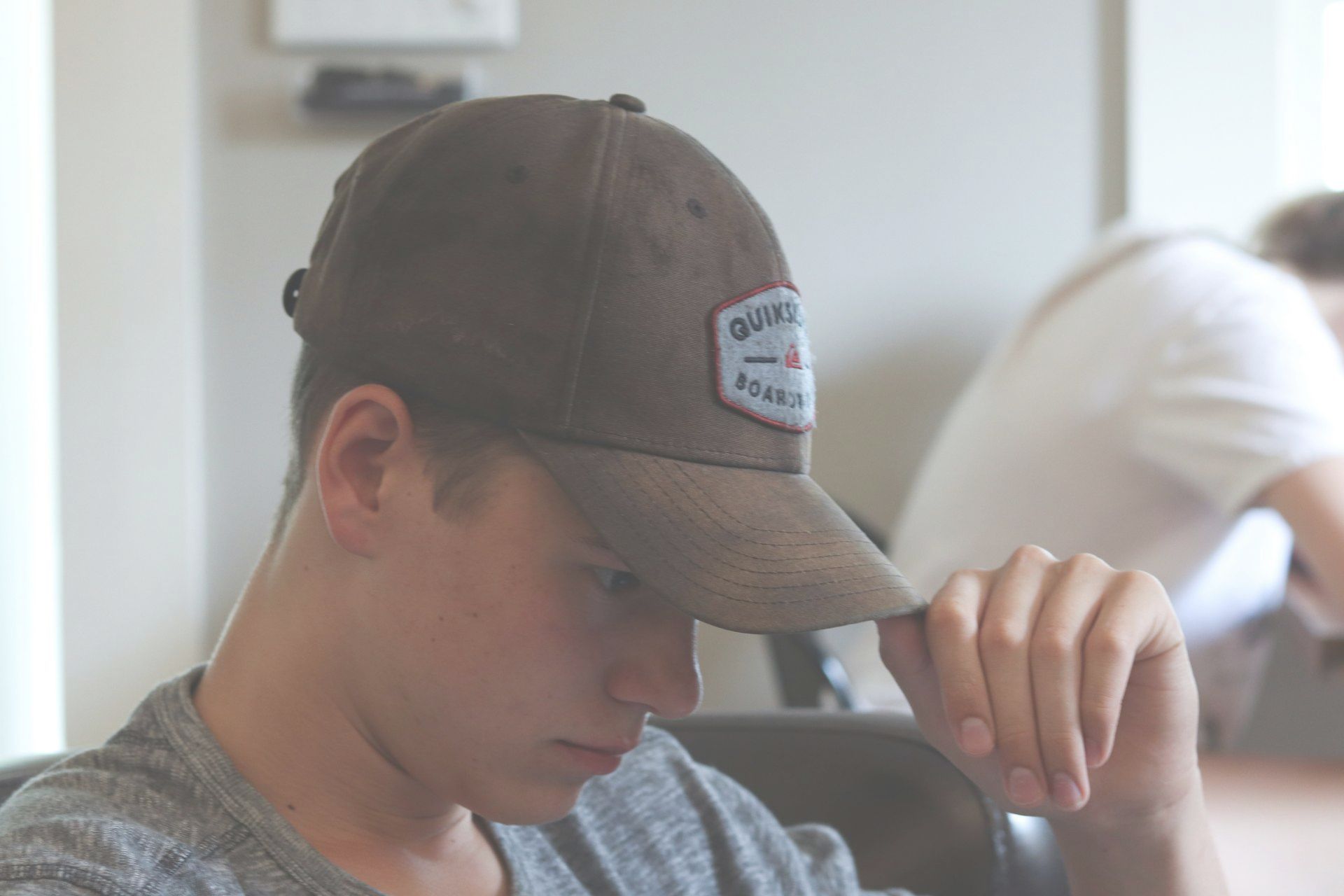 A young man wearing a baseball cap is sitting in a chair.